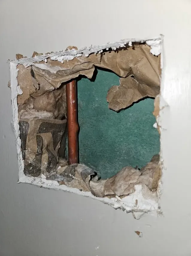 A copper water pipe exposed inside an opened wall where it leaked