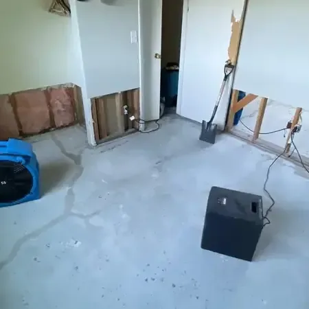 Air movers and a dehumidifier drying a room, lower drywall removed