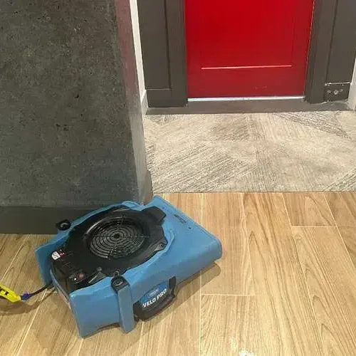 An air mover blowing across a wood-look tile floor beside an open doorway