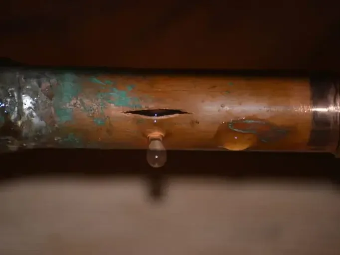 A split copper supply pipe dripping water